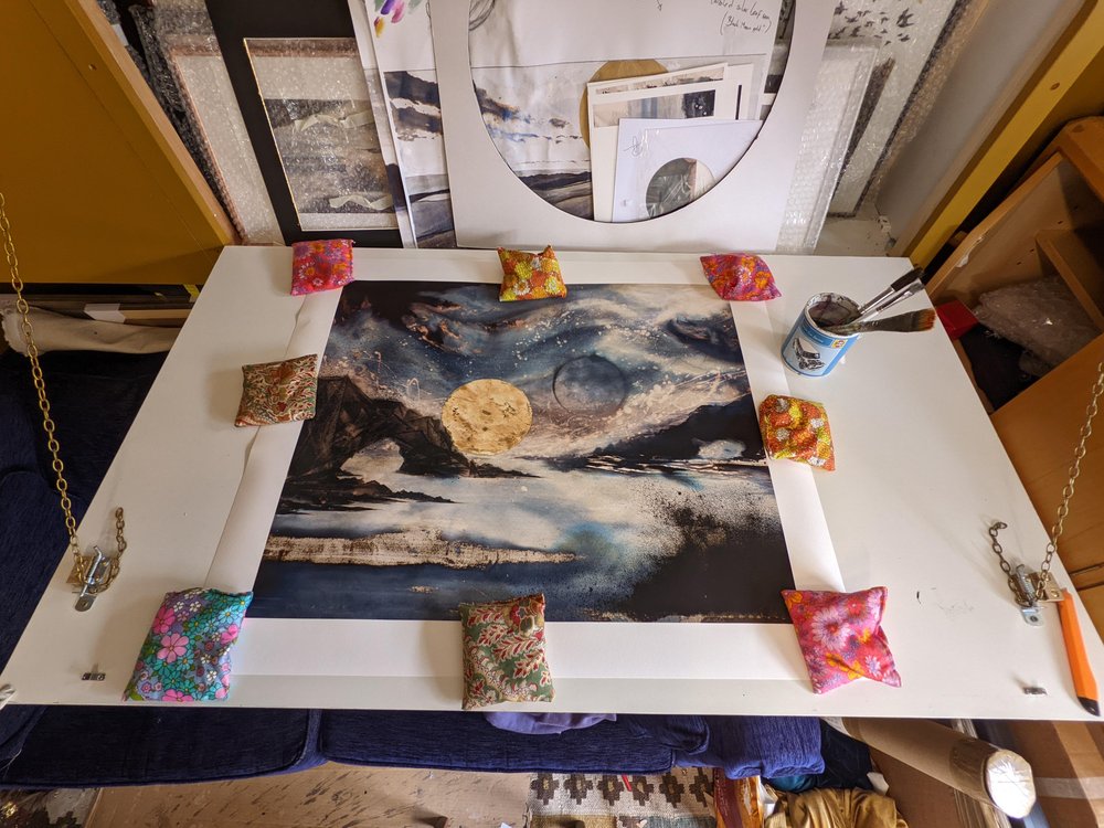 Earth | The sun sets behind an earthly rock formation jutting form the ocean under a kaleidoscopic celestial sky | Hand embellished Print | By Hannah Pugh